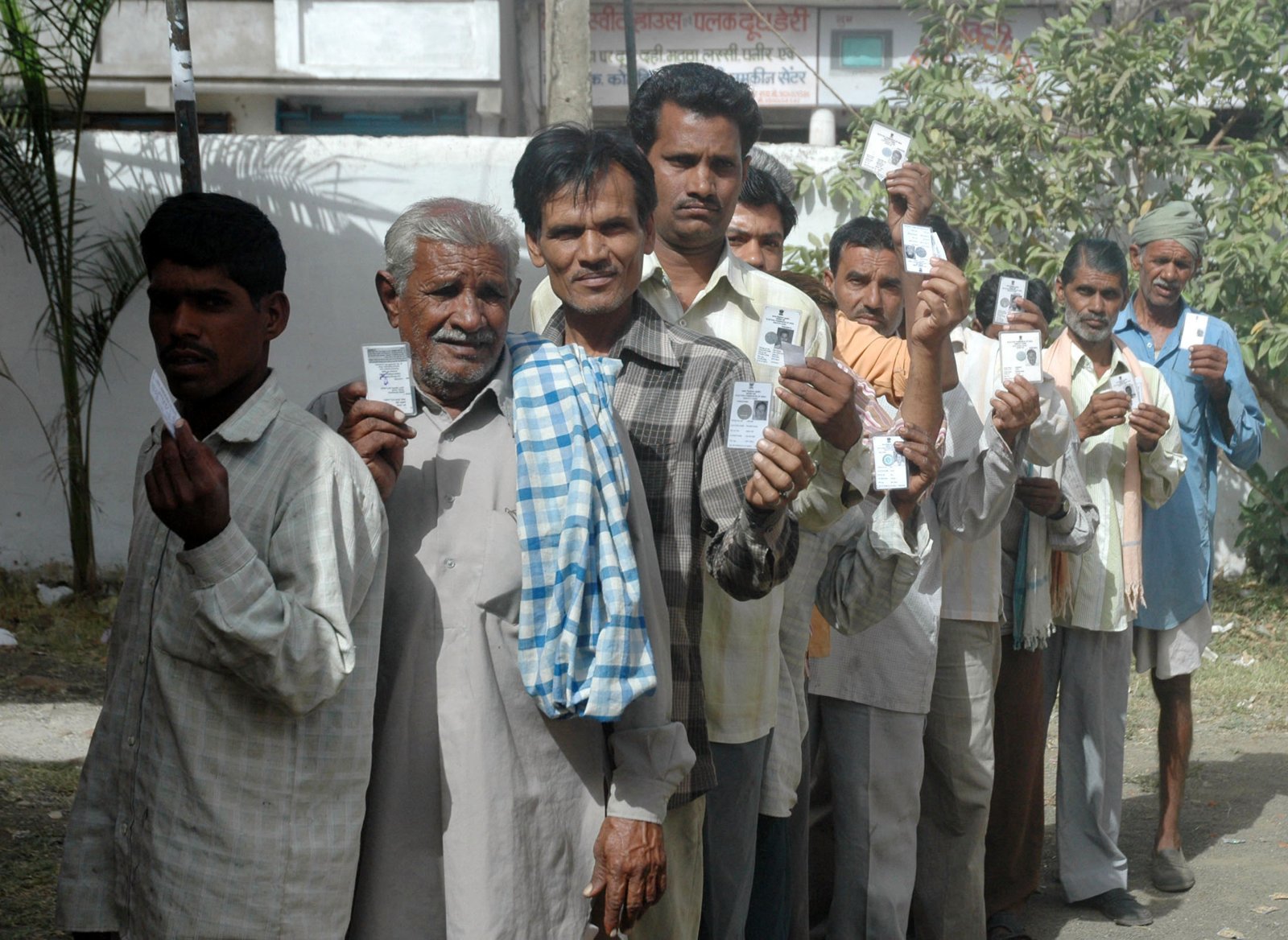 Voters in a queue displaying their voter identity cards at a polling booth in India
